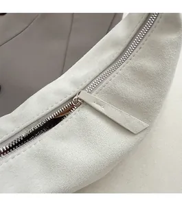 Close-up of smooth metal zipper and premium suede leather texture on grey shoulder bag