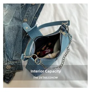 Detail view showing interior capacity of denim crossbody bag with silver chain strap