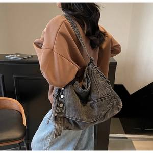 Detail view of large grey denim tote bag with metallic buckles and adjustable strap