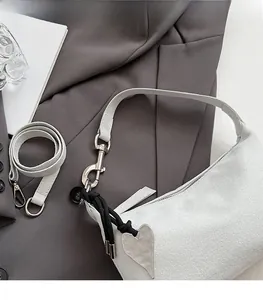 Detail view of suede shoulder bag with heart pendant and silver hardware on a blazer