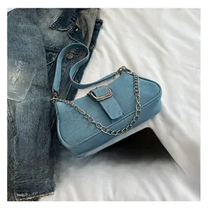 Flat lay of small light blue denim shoulder bag with metal chain and buckle detail