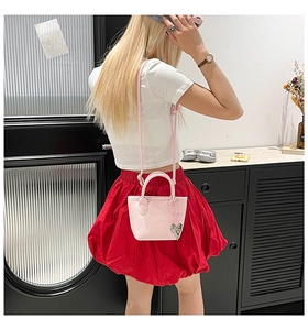 Détail d'un mini sac seau rose avec texture litchi et pendentif en forme de cœur