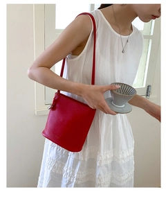 Détail du sac seau en cuir rouge grainé avec logo et design minimaliste élégant