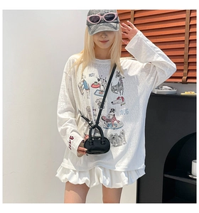 Detail of a minimalist white oversized tee with cartoon prints and a black mini crossbody bag