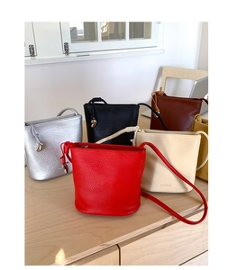 Détail de sacs seaux en cuir grainé avec logo de marque en plusieurs coloris