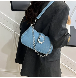 Detail of light blue denim shoulder bag with silver chain and buckle on model