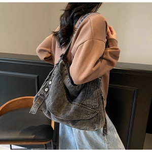 Close-up of a large grey washed denim tote bag with silver buckles shown on a model