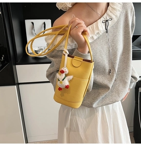 Detail of bright yellow bucket bag with textured leather and cute duckling pendant