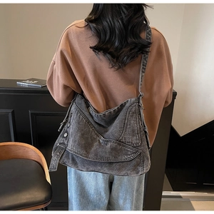 Detailed view of wide strap dark grey washed denim tote bag worn by a model