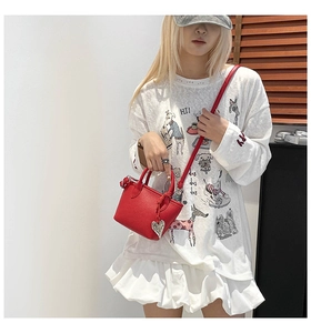 Chic red mini bucket bag with silver heart charm shown in a soft lifestyle setting