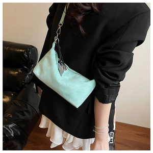 Detailed view of mint green suede underarm bag with heart charm and woven strap detail