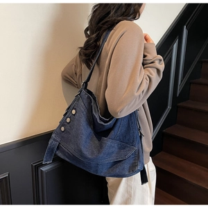 Side view of large denim tote bag with silver buckle details and raw edge stitching