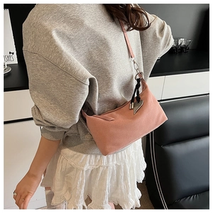 Detail of pink canvas hobo bag featuring a crescent shape and heart metal pendant