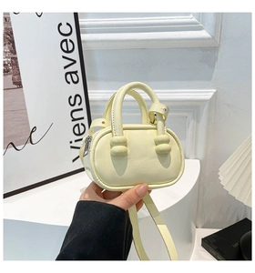 Micro cream bowling bag with dual handles and long shoulder strap in a minimalist style