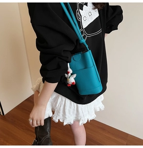 Detailed view of light blue lychee pattern bucket bag with cute duck charm on a model