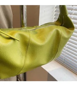Detail of neon green leather shoulder bag showing soft pleated texture and silver zipper