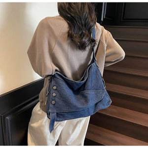 Detail shot of navy denim tote bag with decorative metal side buckles on stairs