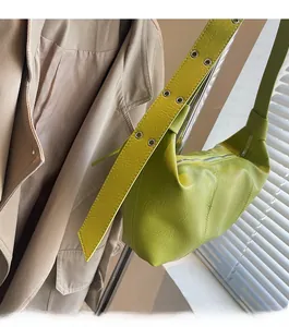 Macro shot of green hobo bag featuring wide strap with metal eyelets and litchi texture
