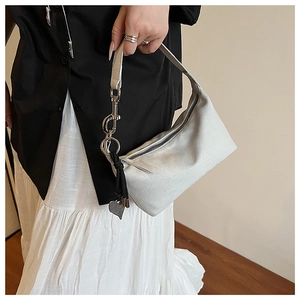 Detail of white matte baguette bag with silver hardware and heart charm accessory