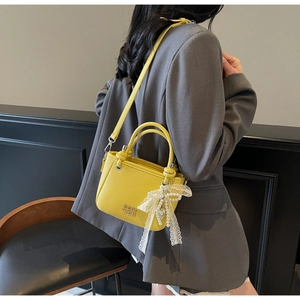 Detail of yellow lychee texture leather bucket bag with pearl lace bow charm and strap