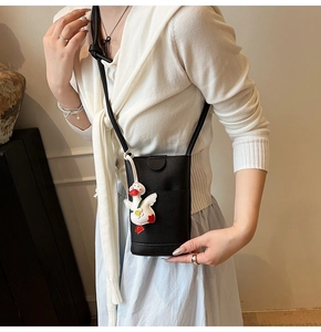 Détail du mini sac bandoulière noir grainé avec un pendentif canard blanc mignon