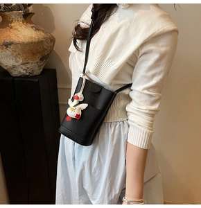 Detail view of a black pebble leather crossbody phone bag with cute duck charm