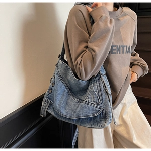 Detail of vintage washed blue denim tote bag with silver button and cargo pocket accents