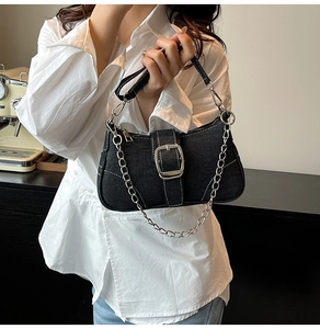 Detail of black denim baguette bag featuring silver metal buckle and chain shoulder strap