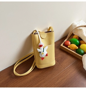 Detail van gembergele lederen telefoontas met een schattige eendenhanger