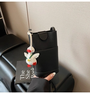 Détail d'un mini sac seau en cuir grainé noir avec un adorable pendentif canard blanc