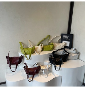 Multi-color display of glossy PU leather crescent bags on minimal stands with wide straps