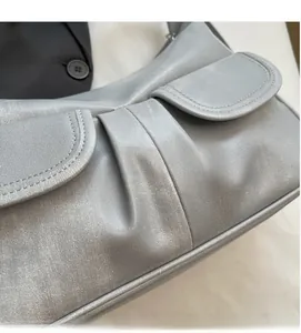 Detail of grey textured faux leather shoulder bag with ruched design and stitching
