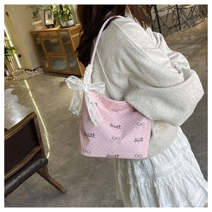 Dettaglio borsa rosa a pois con grande fiocco in pizzo bianco e scritte decorative