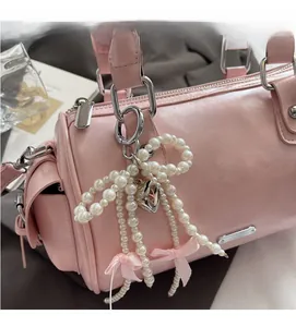 Detail of pink Boston bag featuring pearl bow charm and silver metallic hardware