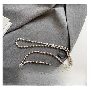Detail of silver beaded metal chain strap with black button on grey blazer fabric
