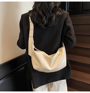 Close-up of cream leather hobo bag with wide grommet strap worn by a model