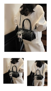 Close-up of black glossy cylinder bag with pearl bow and pink ribbon detail