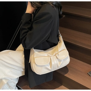 Detail view of retro cream crossbody bag with dual pockets on dark wood background