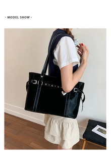 Detail of black glossy bucket bag featuring Y2K metal buckles and silver heart charm
