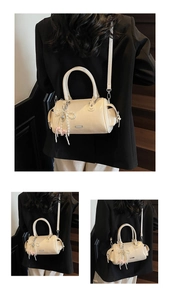Detail of beige Boston bag with pearl bow pendant and metallic shoulder strap hardware