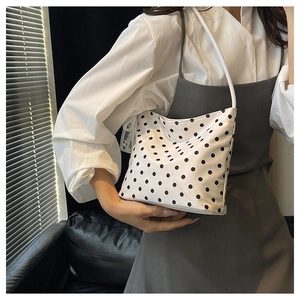 Borsa a spalla a pois indossata da una persona in un interno luminoso con luce laterale