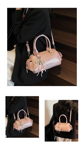 Detail view of pink glossy Boston bag with pearl bow charm and detachable shoulder strap