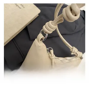 Detail of cream shoulder bag with knotted strap and silver circular hardware ring