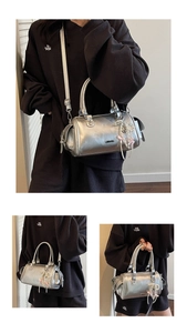 Detail of silver boston bag featuring pearl chain and pink bow charm for casual wear