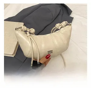 Detail of off-white croissant bag with pleated design and knotted shoulder strap