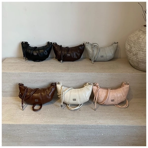 Multiple colors of moon-shaped crossbody bags displayed on minimalist stone stairs