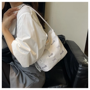 Dettaglio della borsa tote bianca a pois con bordi in pizzo e motivi a fiocco dolce