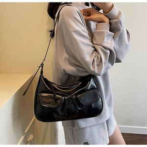 Detail of minimalist black hobo bag featuring dual front pockets and adjustable strap