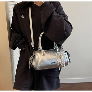 Close-up of silver cylinder bag with pearl charms and pink bows for Y2K fashion style