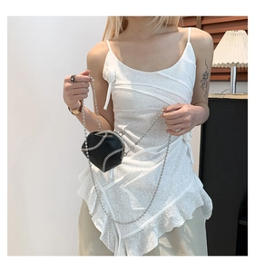 Detail of a mini baseball shaped crossbody bag with white stitching and silver chain